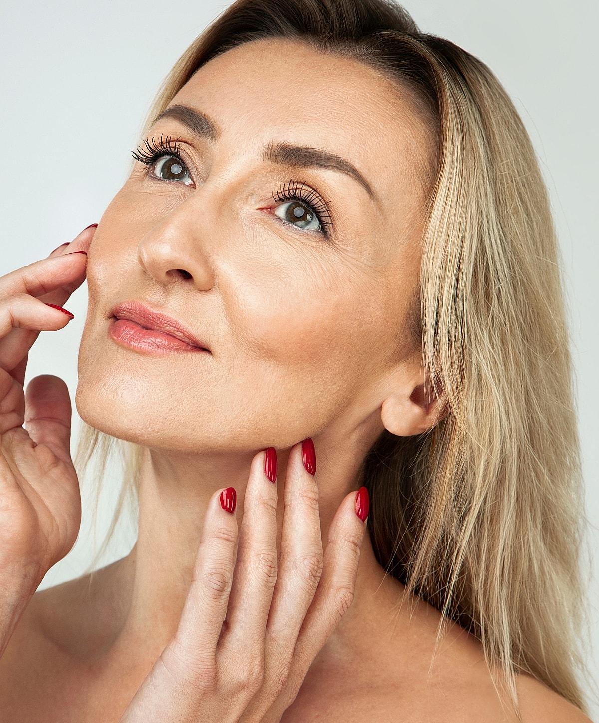 Lafayette blepharoplasty model with blonde hair and red nails.