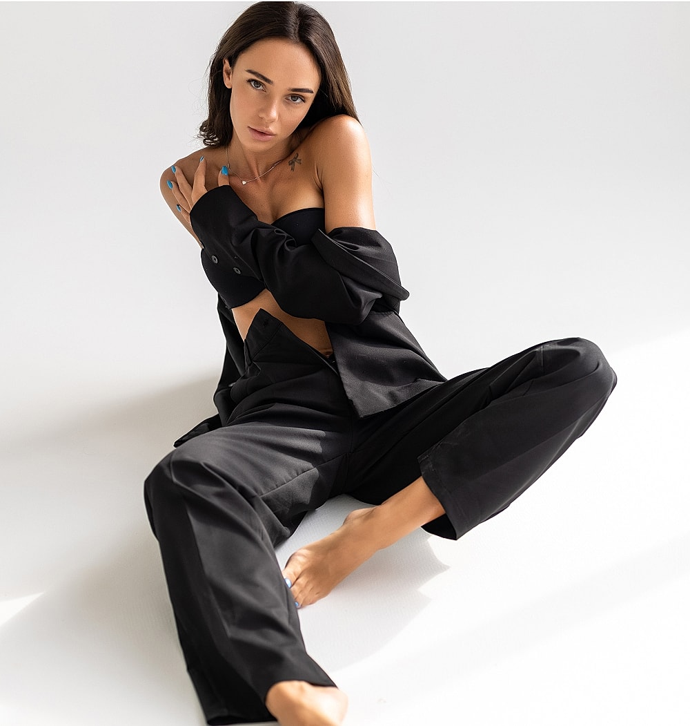 Model in black outfit sitting gracefully.
