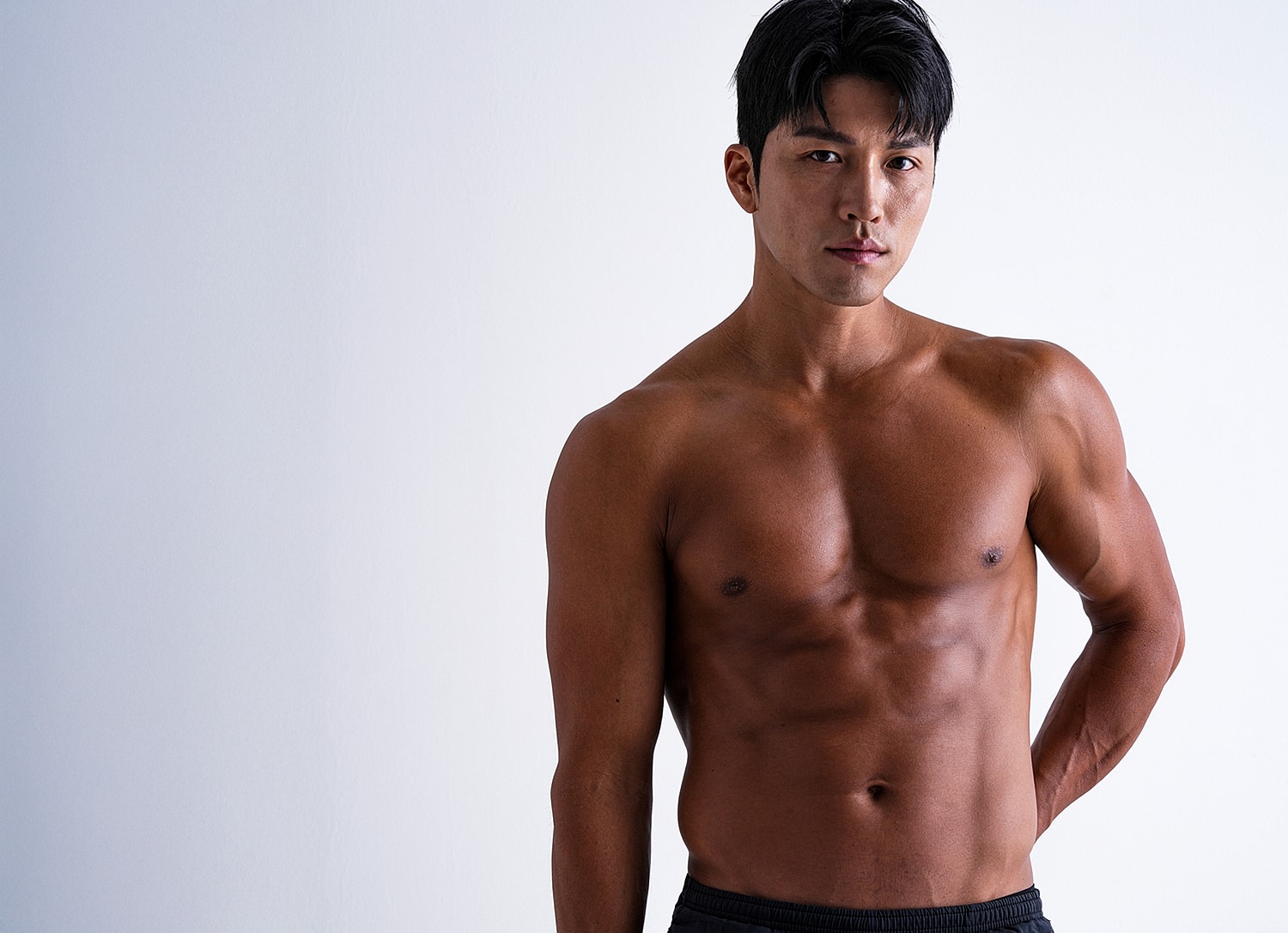 Man posing with strong physique on white background.
