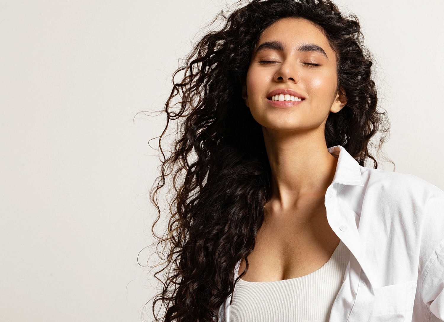 Smiling woman with curly hair and glow.