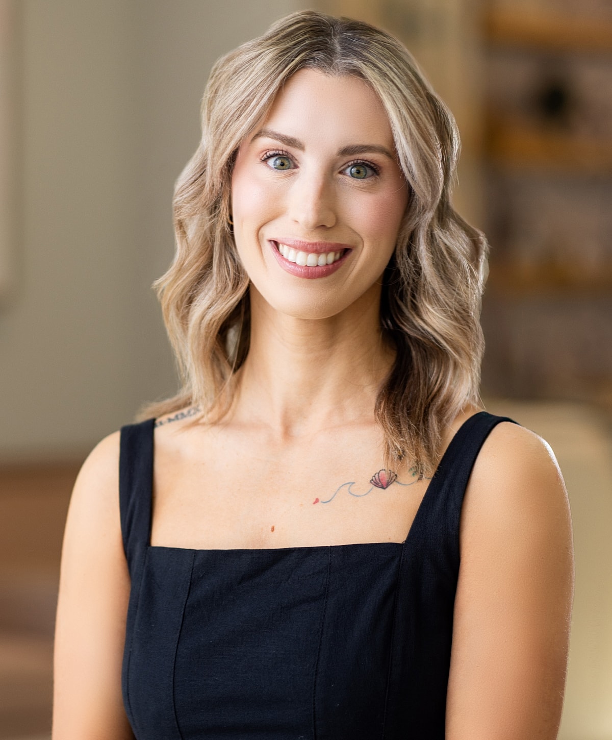 Smiling woman with blonde hair and tattoo.