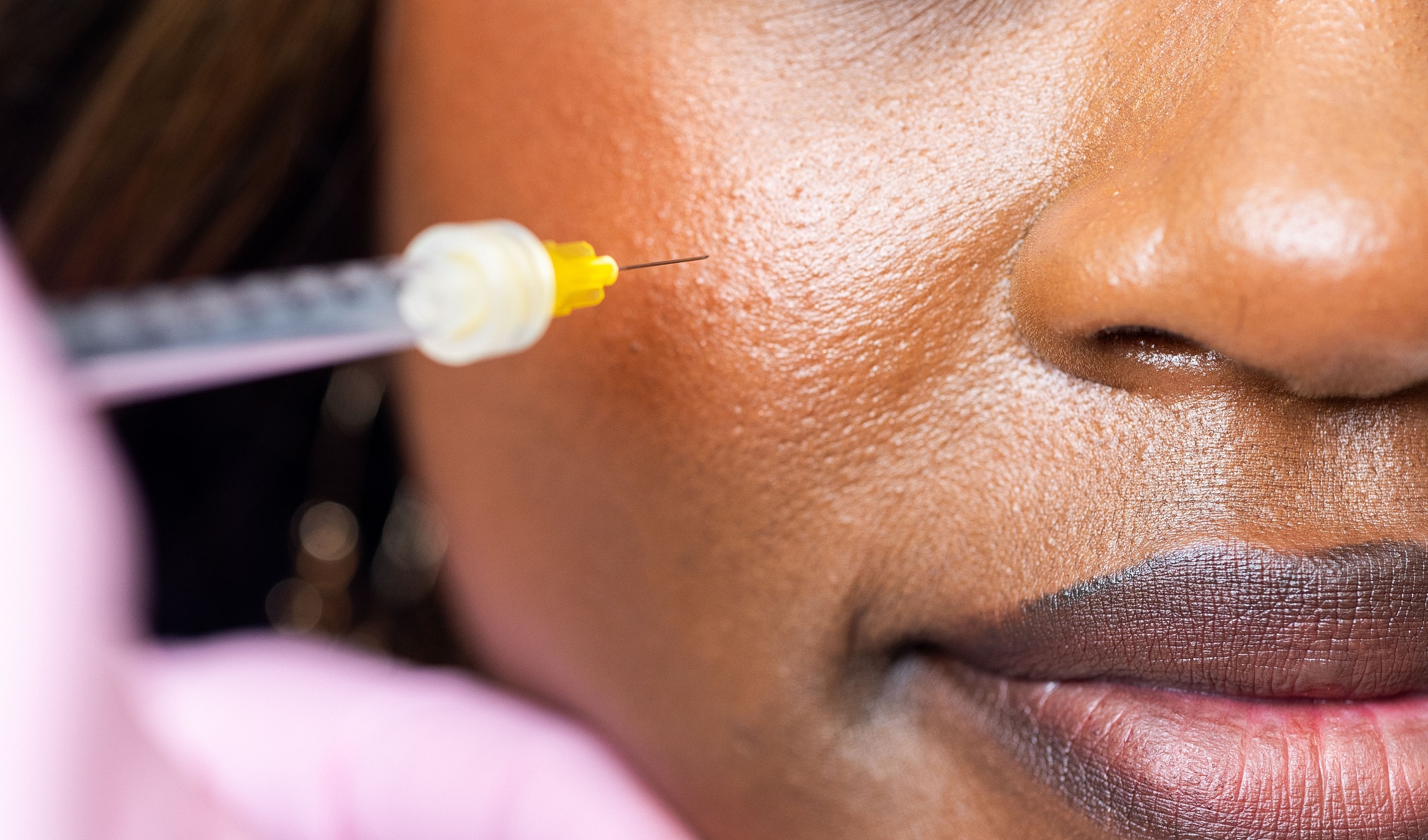 Close-up of syringe near a woman's face.