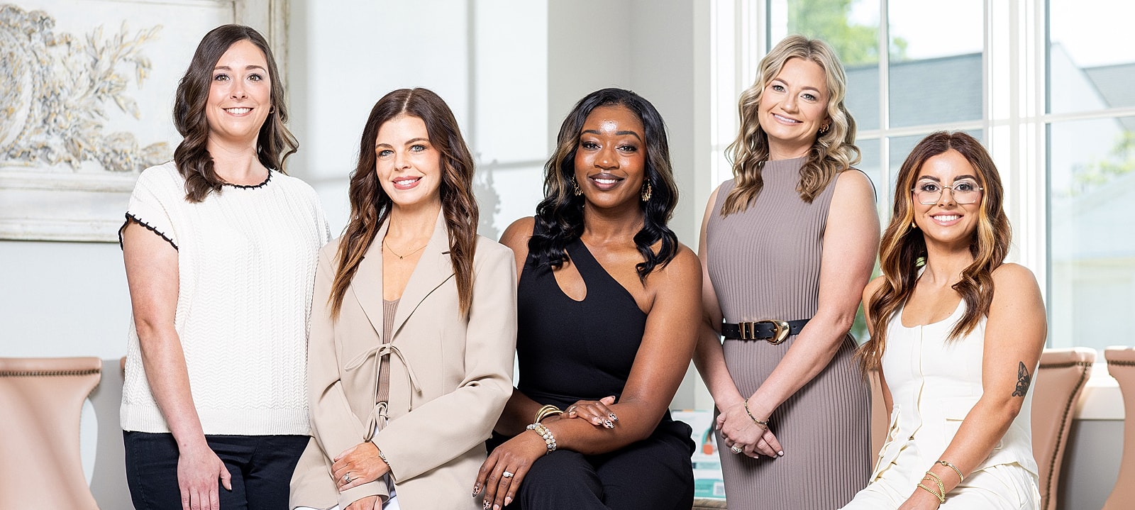 Five women posed together in a well-lit space.